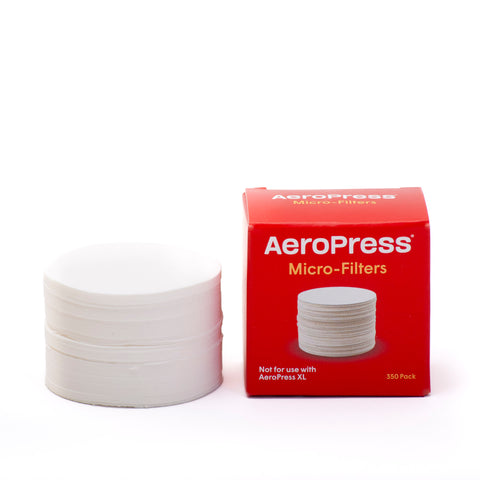 A box of AeroPress filters next to a stack of AeroPress filters.