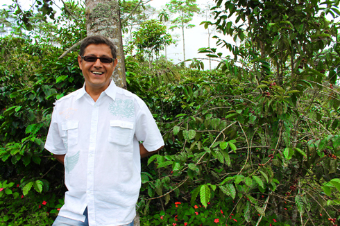 Omar Arango smiling broadly in front of his coffee trees